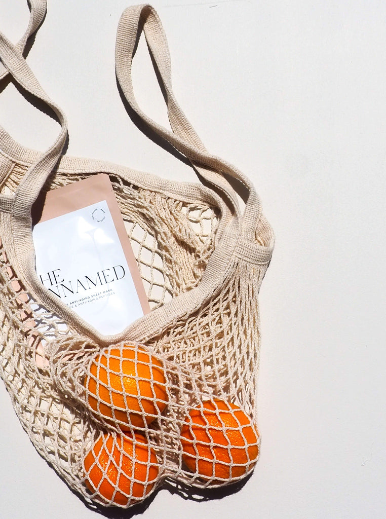 The Unnamed Skincare Brightening Face Sheet Mask in Shopping Bag with Three Oranges
